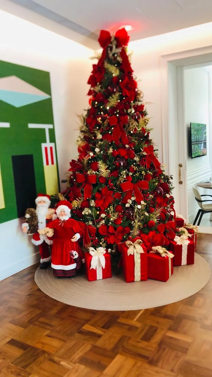 Árvore clássica em vermelho com presentes e bonecos de Papai Noel