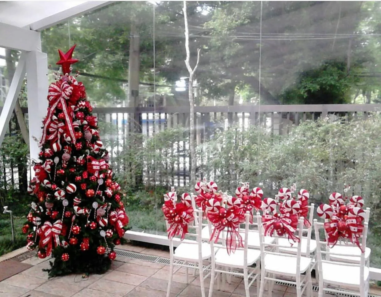 Árvore e cadeiras decoradas com laços listrados em área externa